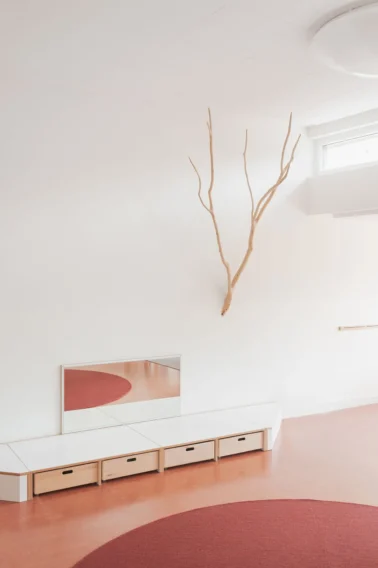 Gruppenraum mit Spielpodest und Dekoast Kindergartenmöbel und Raumgestaltung: Von Papoq gestalteter Gruppenraum mit Spielpodest, Tretford-Teppich und praktischem Stauraum, ideal für vielseitige Nutzung im Kindergarten.