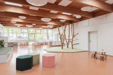 Kita Piazza mit Kletterbäumen Kindergartenmöbel und Raumgestaltung: Große Piazza oder Gemeinschaftsraum in der Kita, vielseitig nutzbar als Essbereich, Bühne und für Kletterbäume, ideal für gemeinsames Spielen und Zusammenkommen.